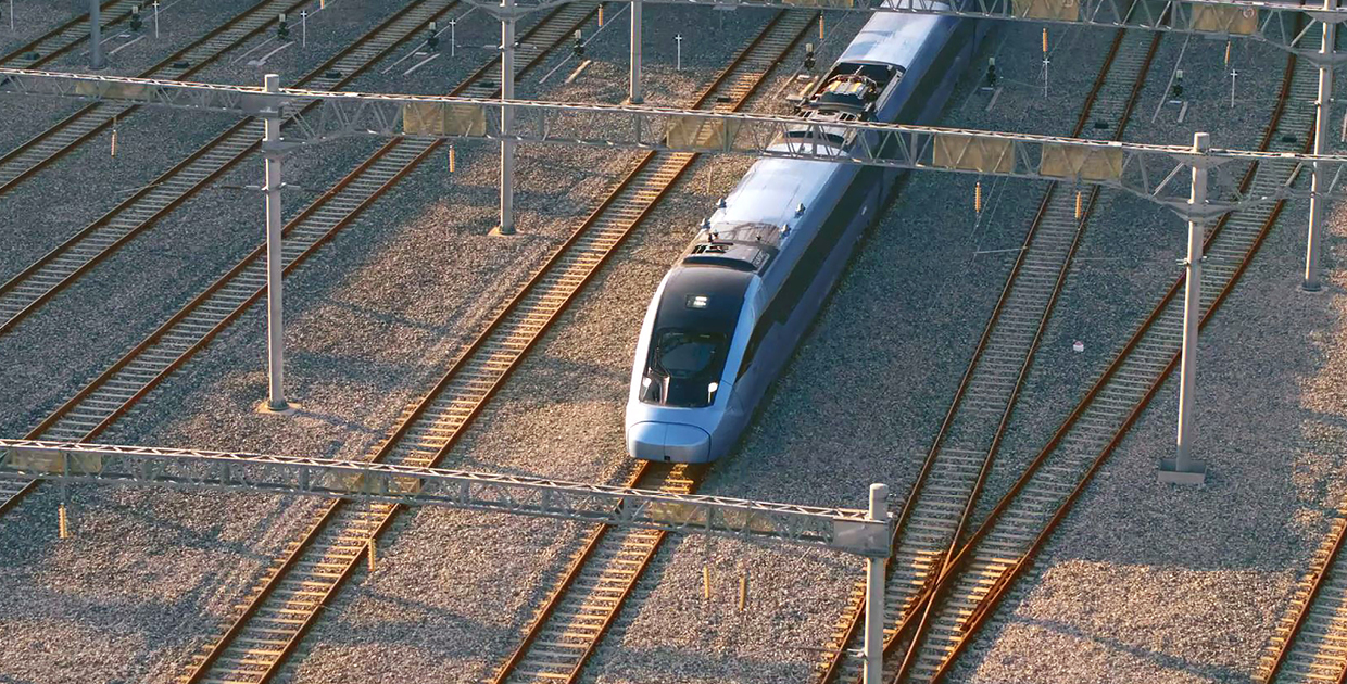Photo of a blue train running on the middle track among several railroad tracks