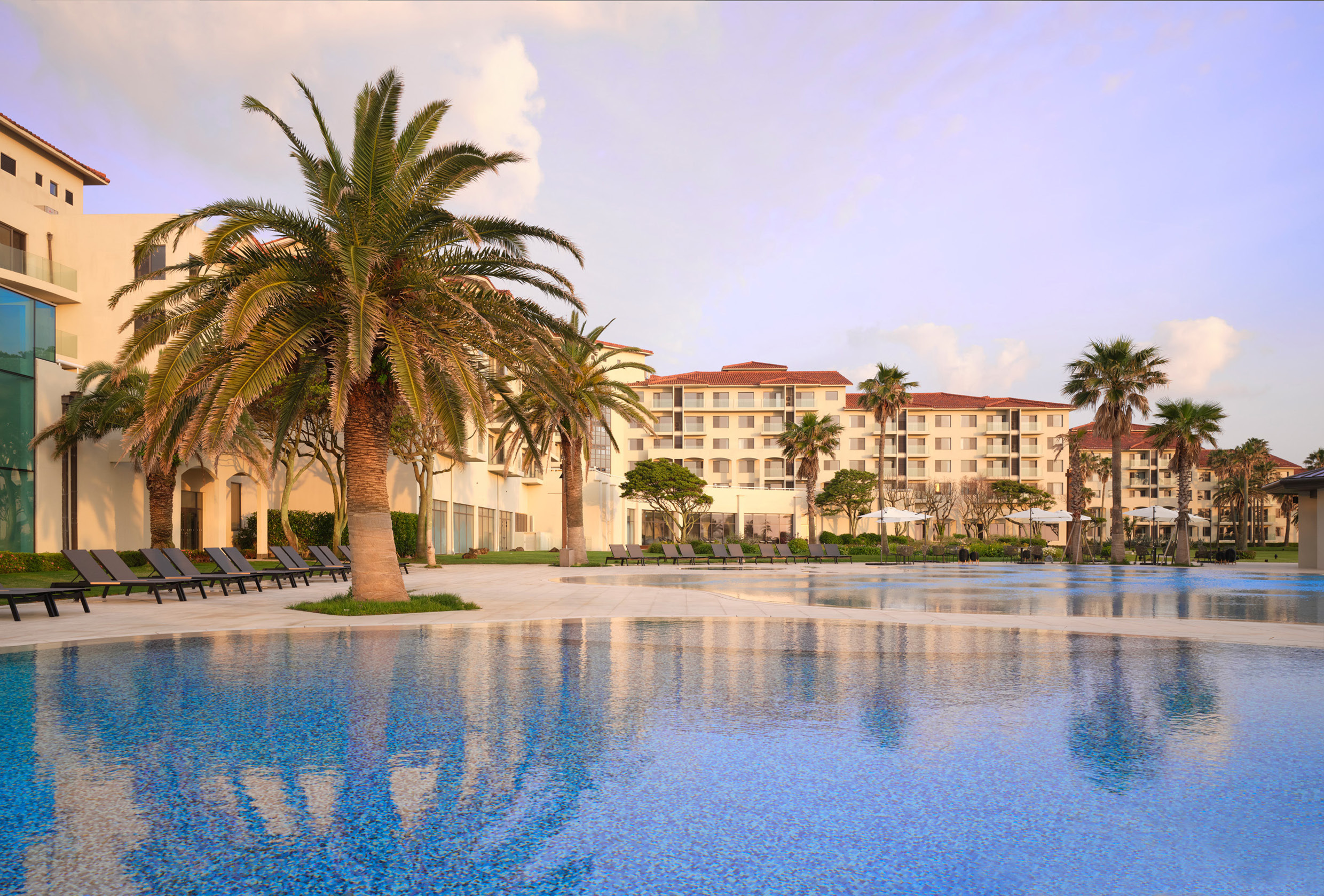 The exterior of the resort and the swimming pool colored red by the sunset light