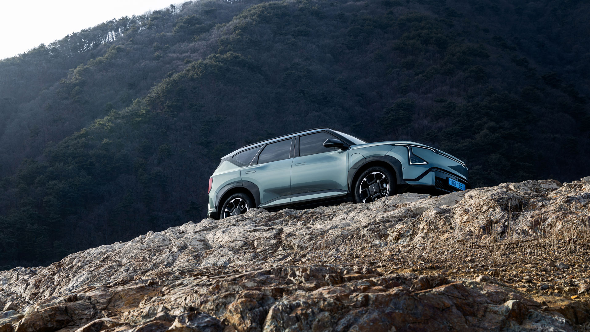 Set against rugged terrain, the Kia EV5 GT-Line stands out with distinctive details and proportions - main