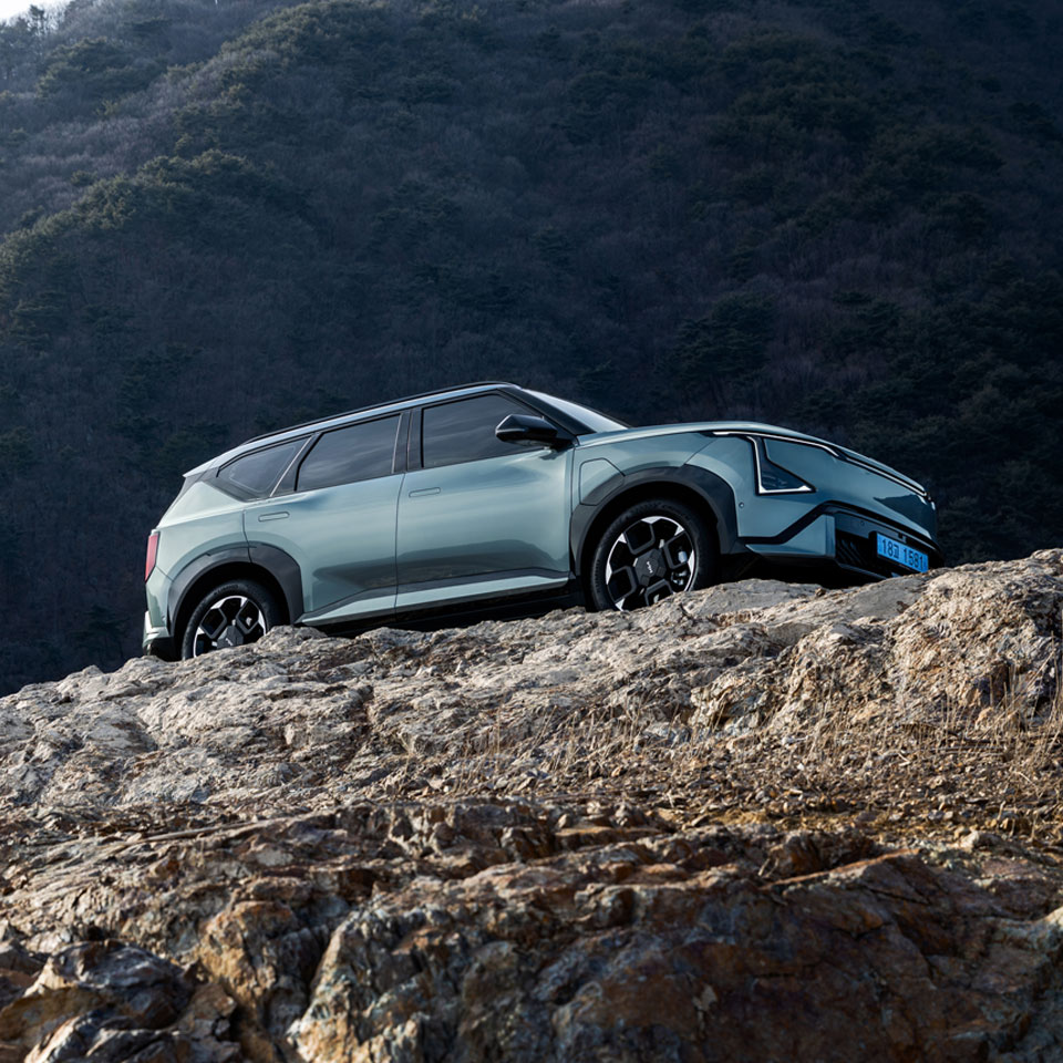 Set against rugged terrain, the Kia EV5 GT-Line stands out with distinctive details and proportions - th