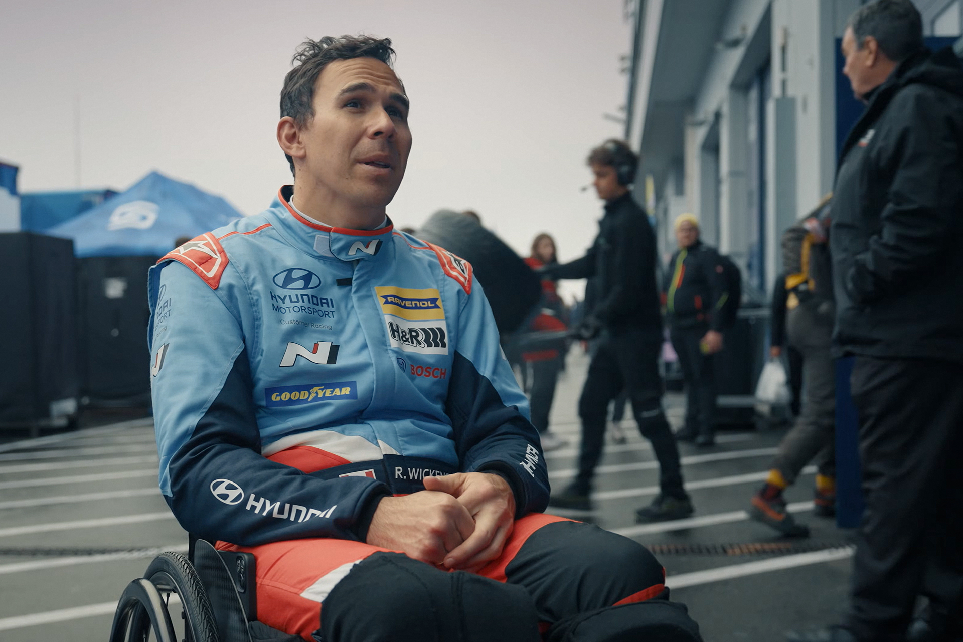 Robert Wickens being interviewed while wearing a racing suit