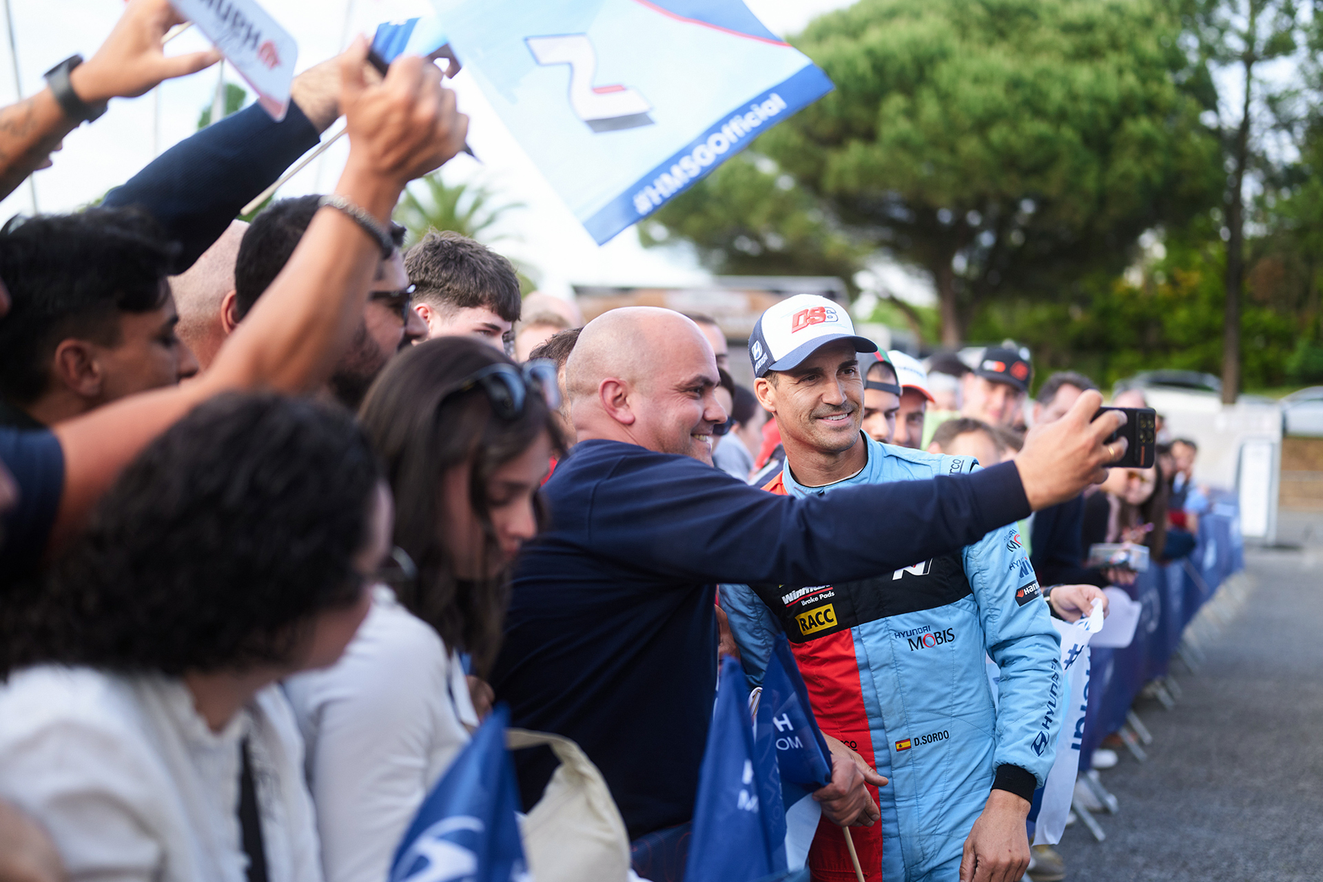 A driver greeting fans and posing for commemorative photos