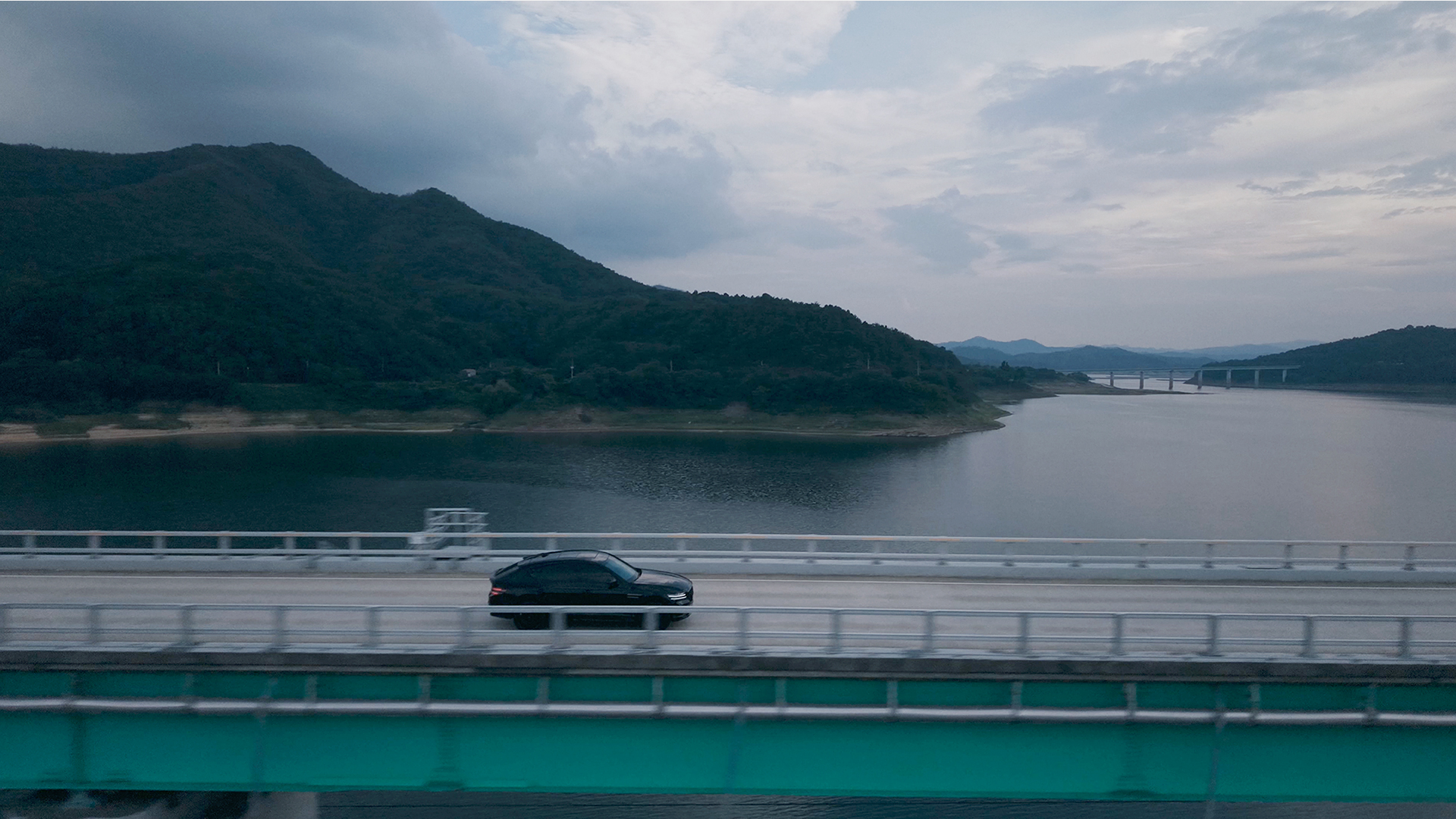Genesis GV80 Coupe driving through scenery along a river