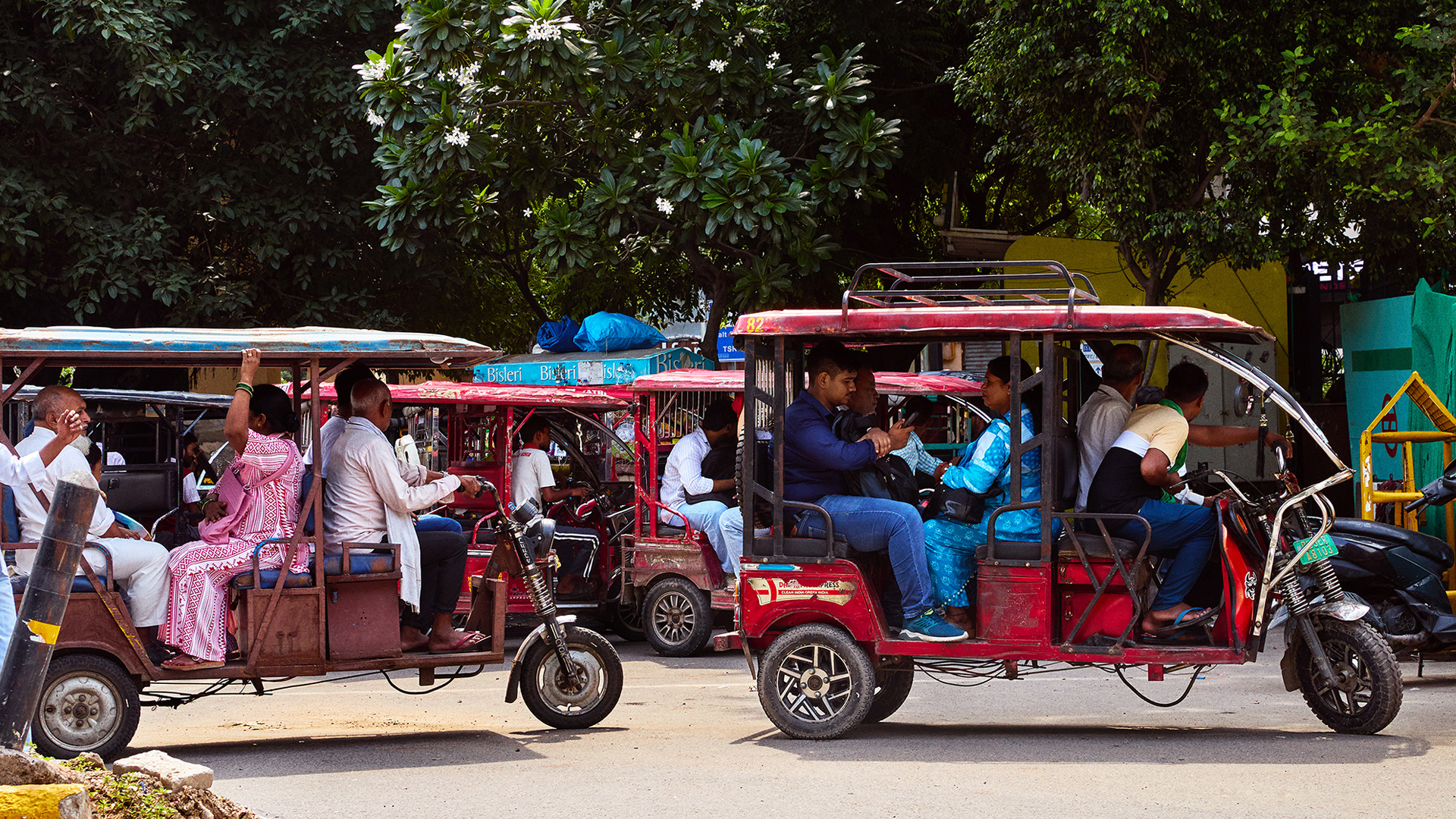 Three-wheeled vehicles and people moving along a street in India