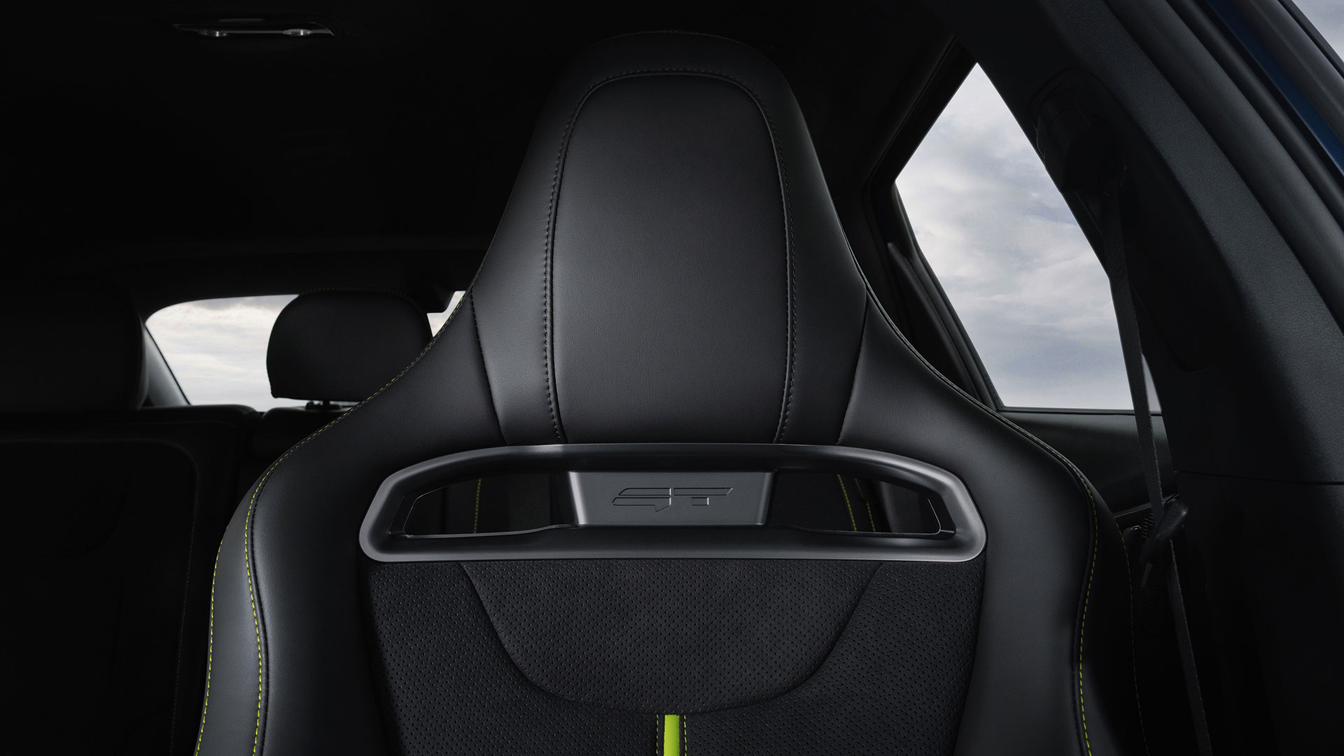 Upper section of a black bucket seat highlighted by a GT logo and neon green stitching