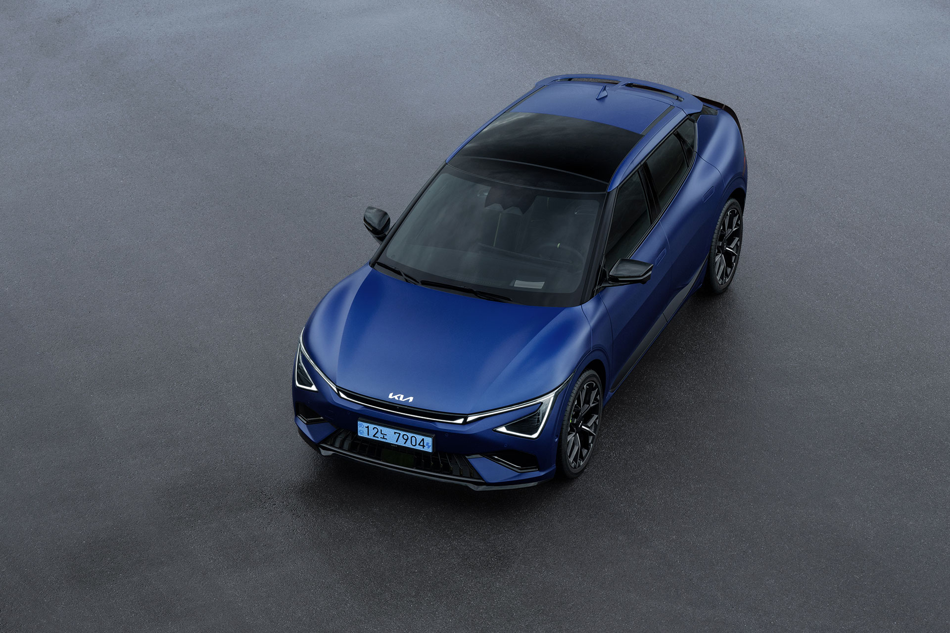 The front and side of a blue EV6 GT, viewed obliquely from above on a dark gray floor