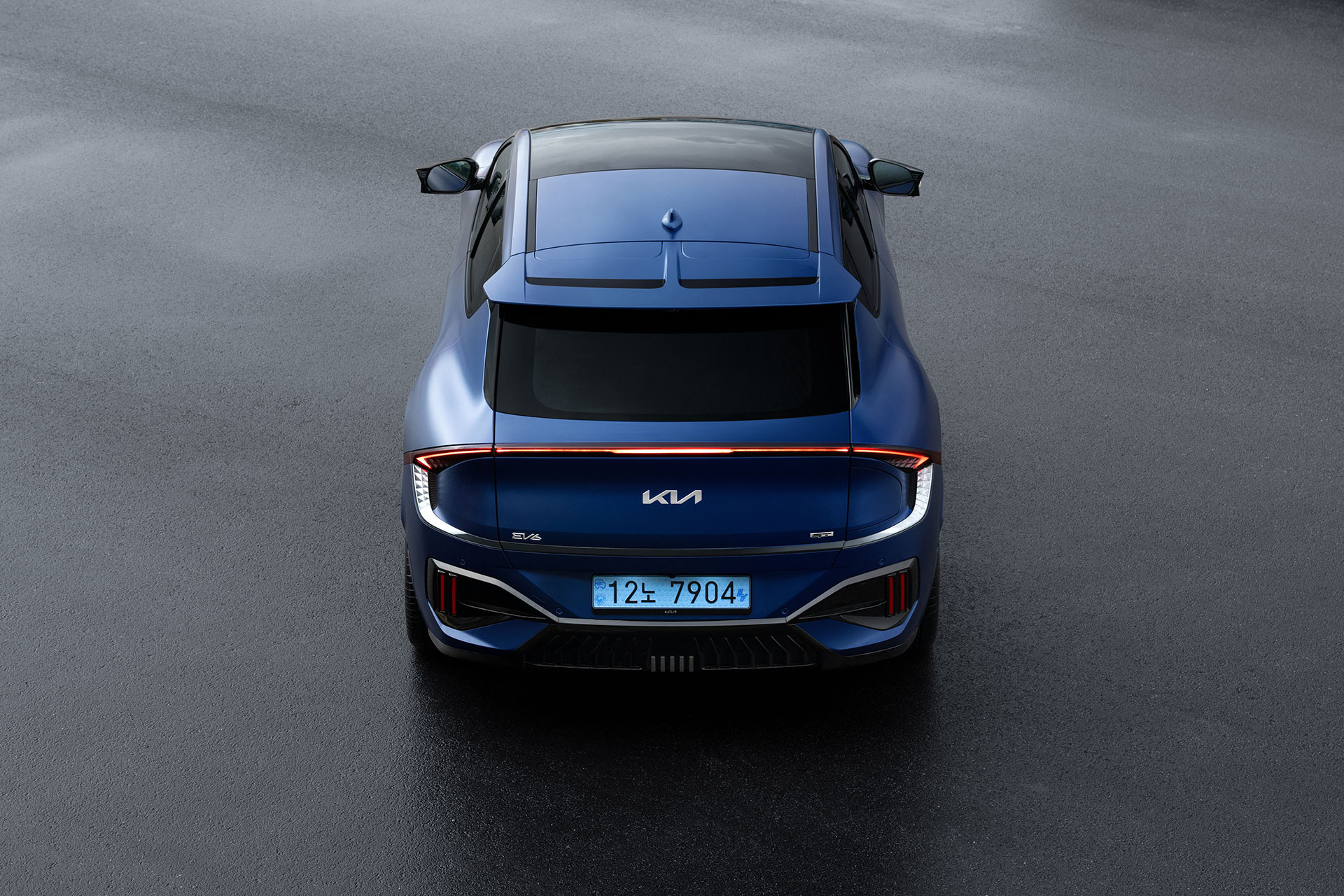 The rear taillights and rear diffuser of a dark blue EV6 GT on a wet road